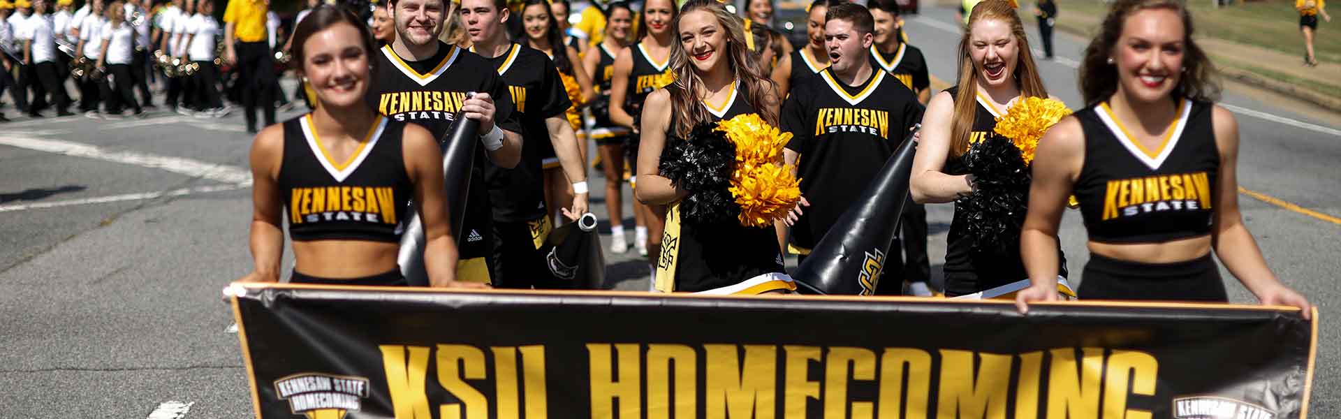 ksu cheerleaders holding the "homecoming" banner in the parade.