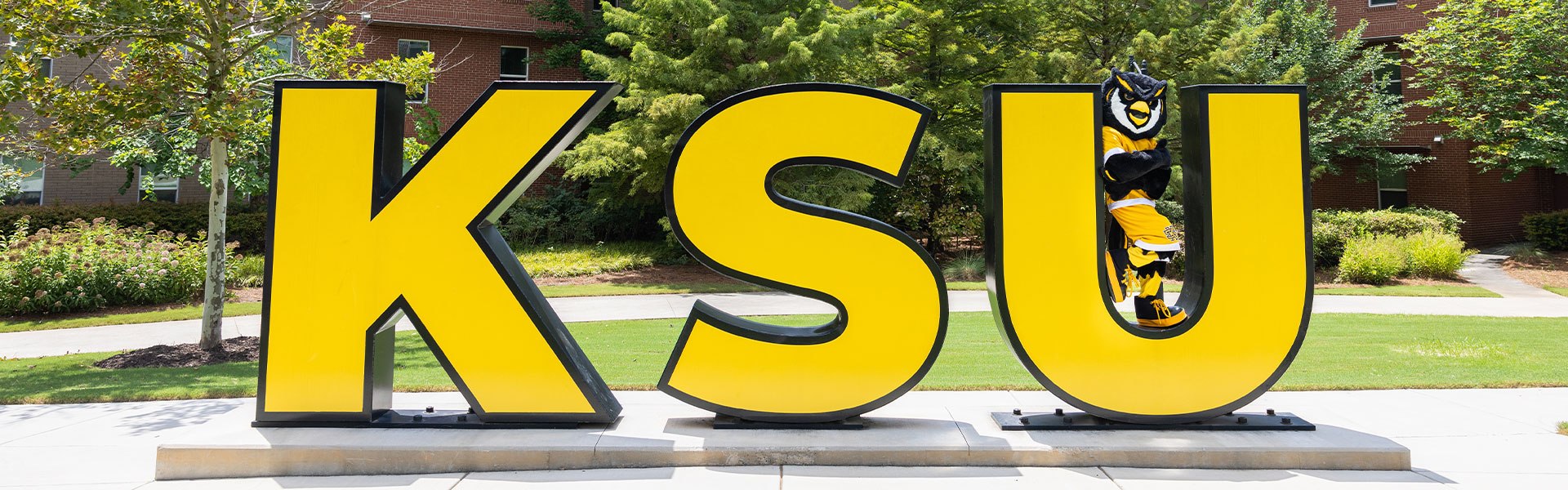 scrappy posing with the ksu sign on campus.