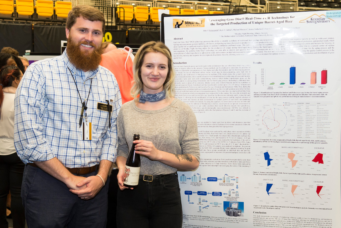 2 students standing by presentation poster