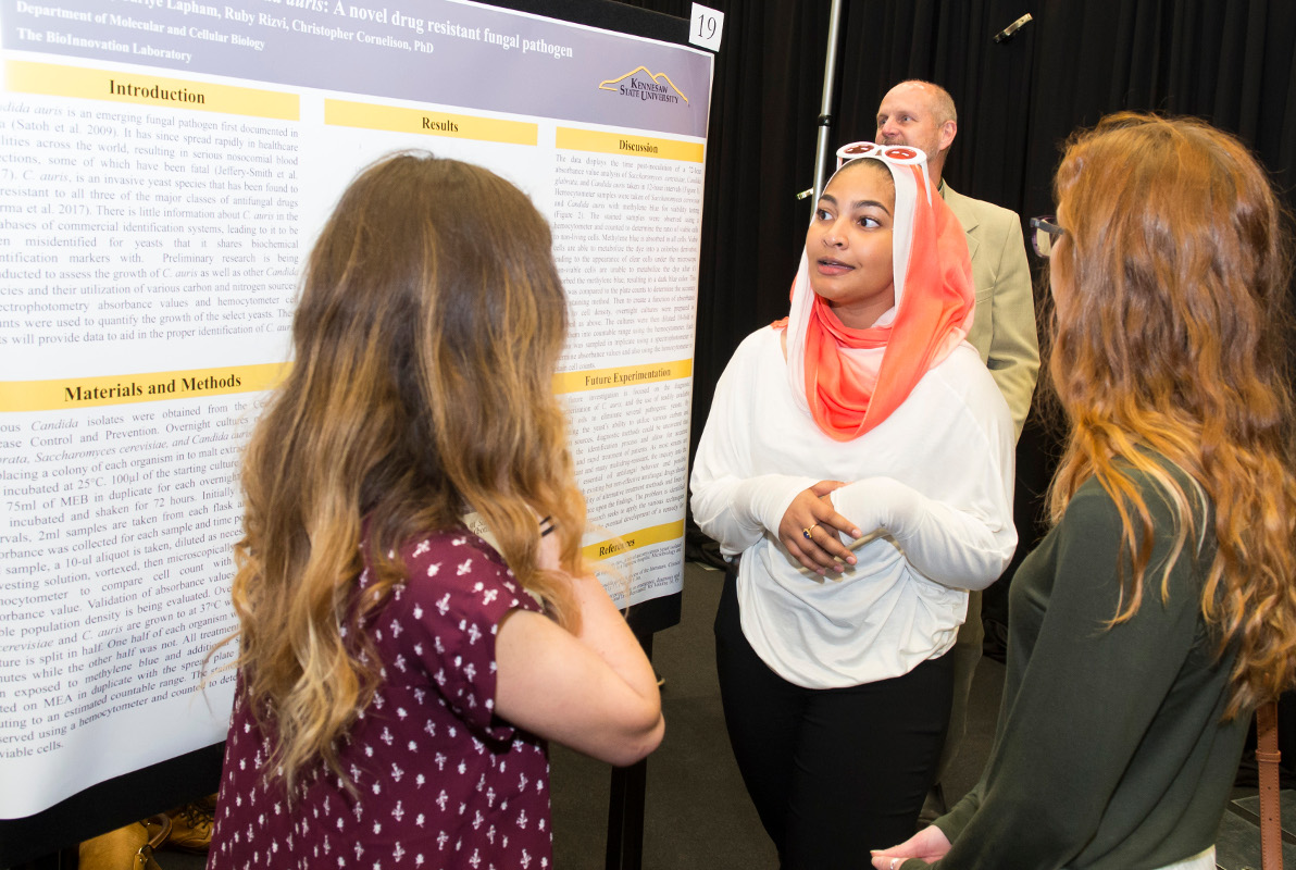 four students standing around a presentation folder