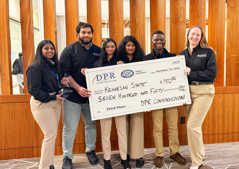 Competition team poses with giant check. 