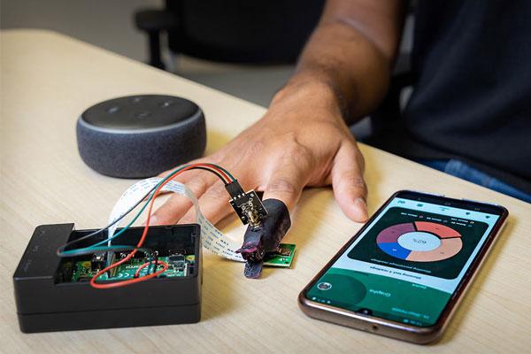 photo of non evasive blood glucose project.  Basically, it shows a computer component connected to users finger and phone with app on screen