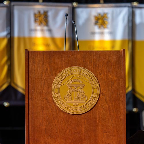 ksu cermony podium with gold presidential seal on the front.