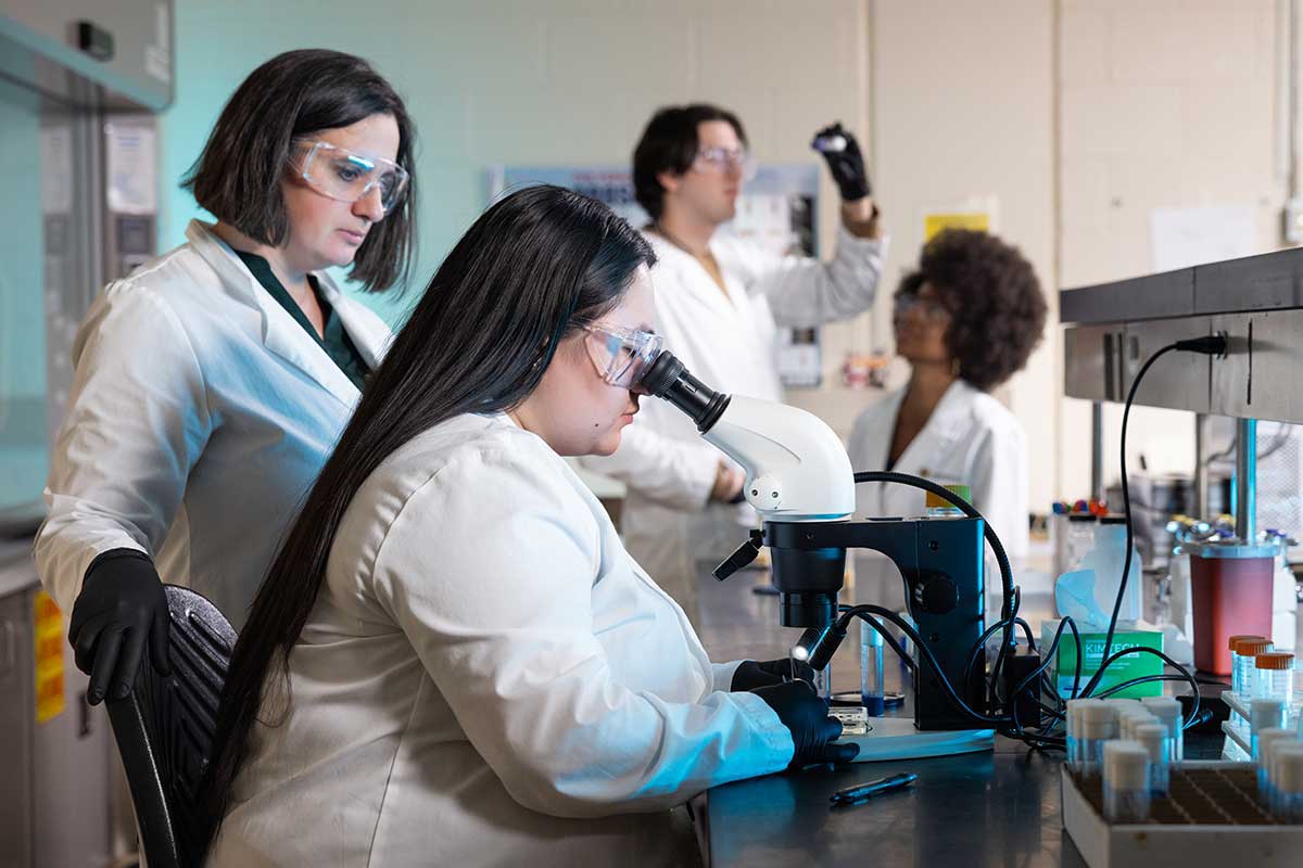 Photo of faculty and students working on research in a laboratory. / Photo of faculty and students working on research in a laboratory.
