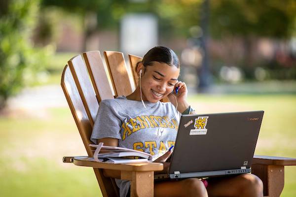 ksu student outdoors using their laptop