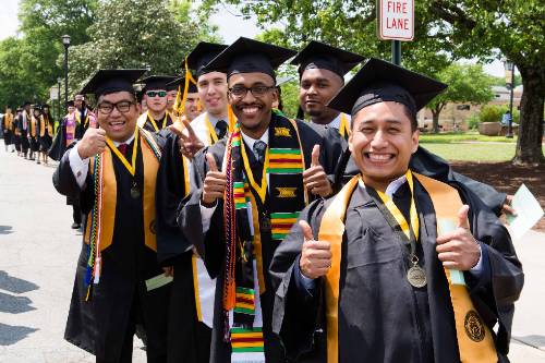 group of graduate students in their cap and gown smiling for picture.