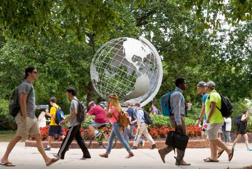 ksu students walking on the marietta campus past the globe statue.