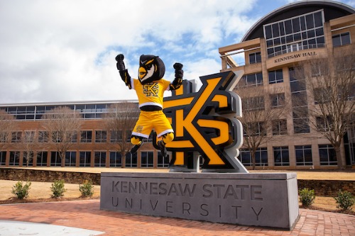 scrappy jumping in front of the ksu statue on campus.