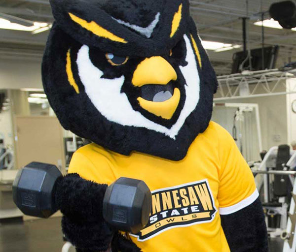 Scrappy the Owl, the Kennesaw State University mascot, is lifting weights in KSU fitness center.