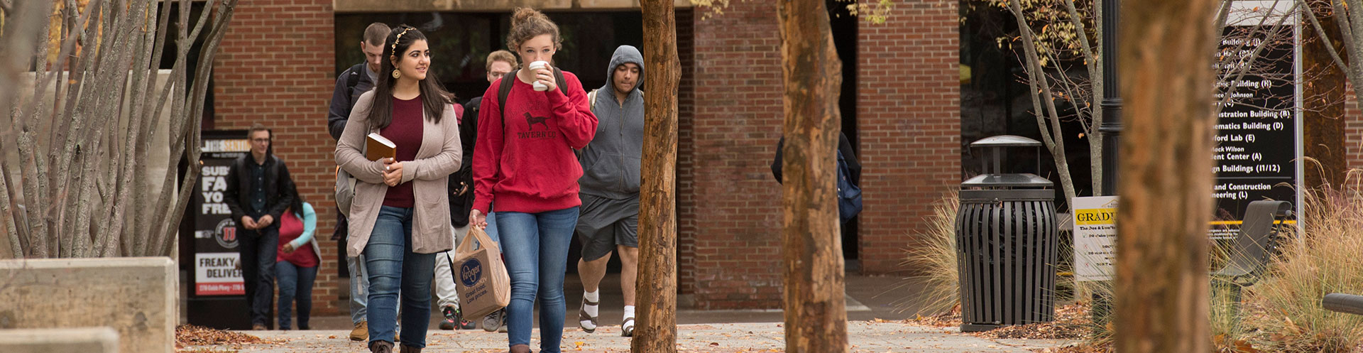 students on ksu campus one in red sweatshirt drinking coffee