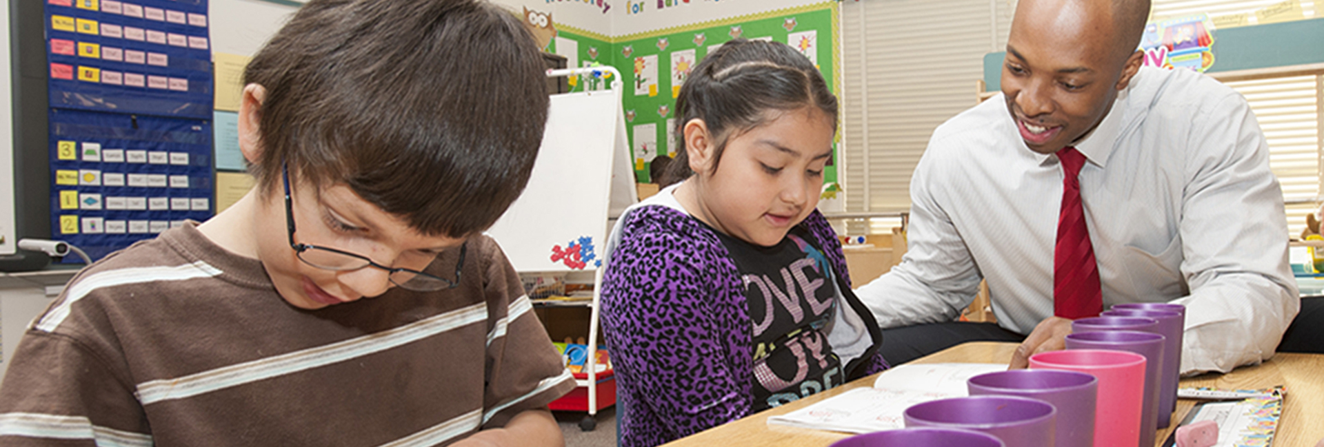 two students use cups to study math with a teacher