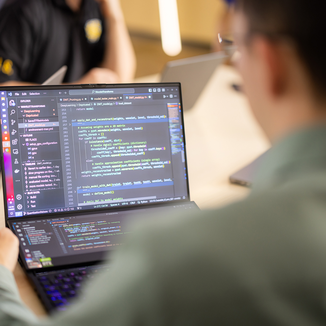 A person holding a laptop with the screen showing computer coding