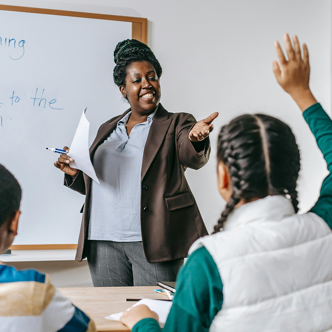 female english teacher asking questions to student raising hand