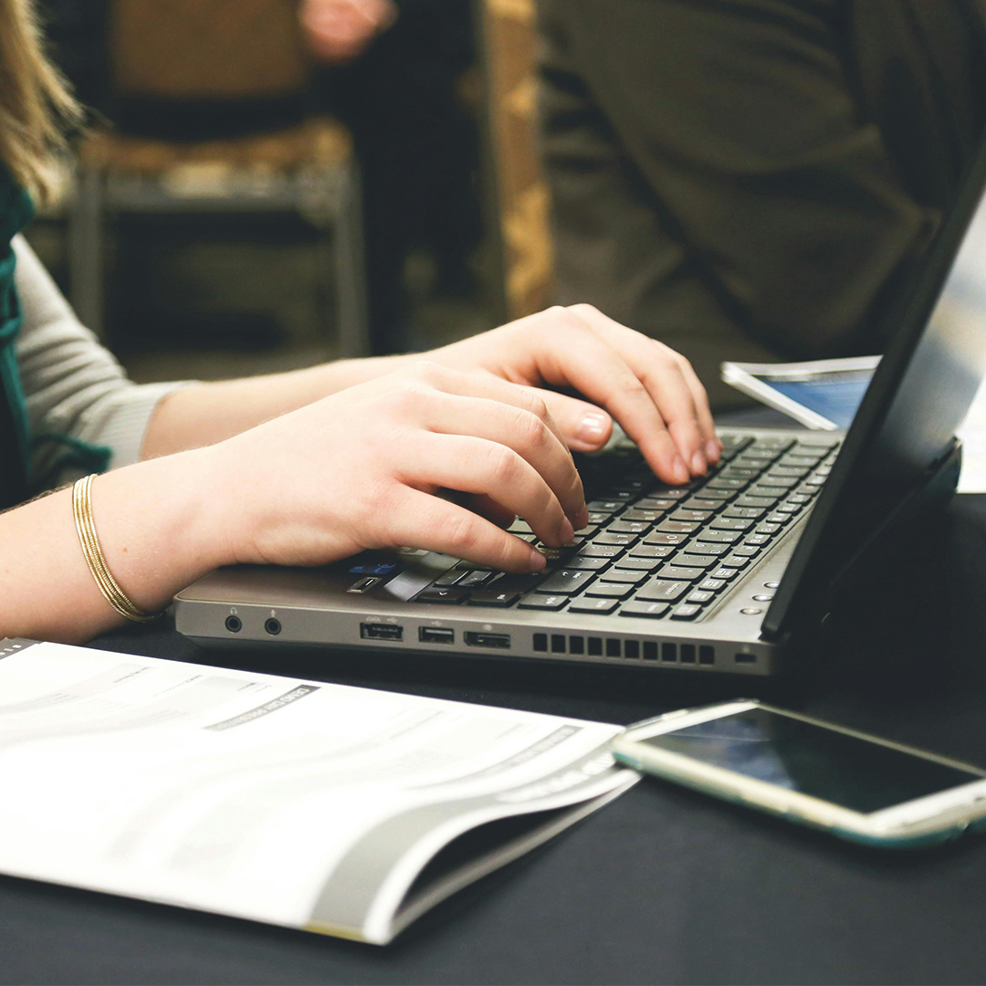 copywriter typing on a laptop on desk