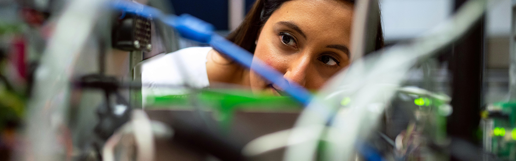 A young woman inspects the inner workings of computer hardware