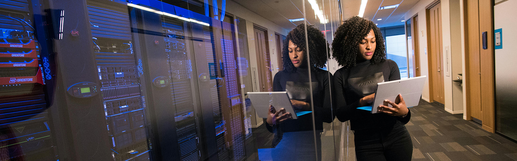 A woman working on a computer next to a large cyber database center