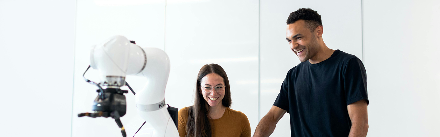 Students using robotic arms while smiling eager to learn