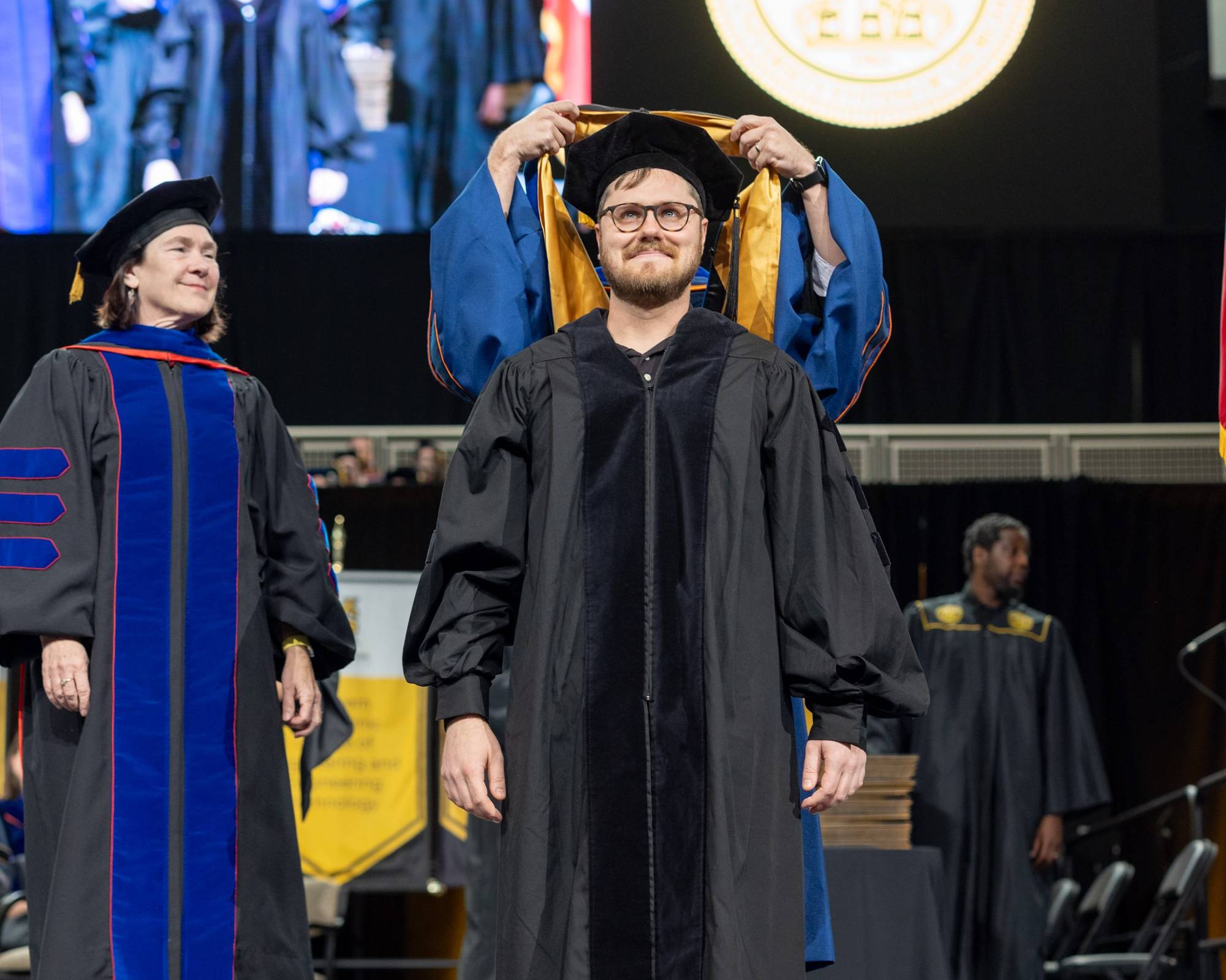 Doctorate student being hooded at commencement ceremony on a stage