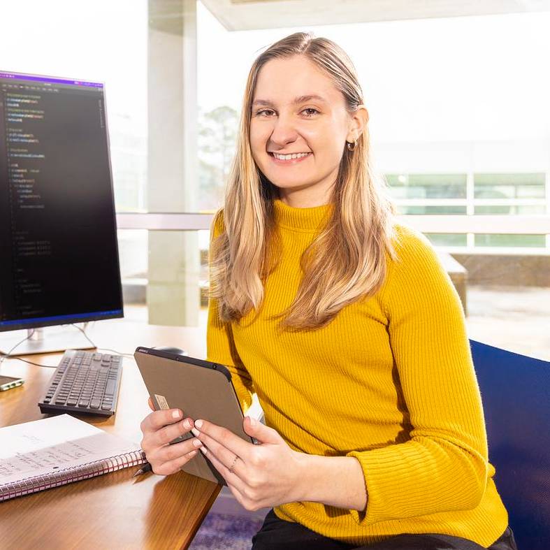 Student in yellow sweater sitting at computer