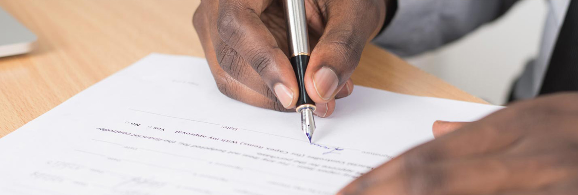 mans hand signing document with fountain pen