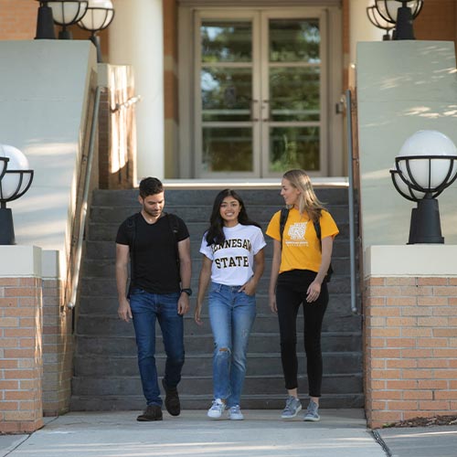 students walking out of a building on campus.