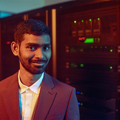 ksu student smiling standing in front of the server room.