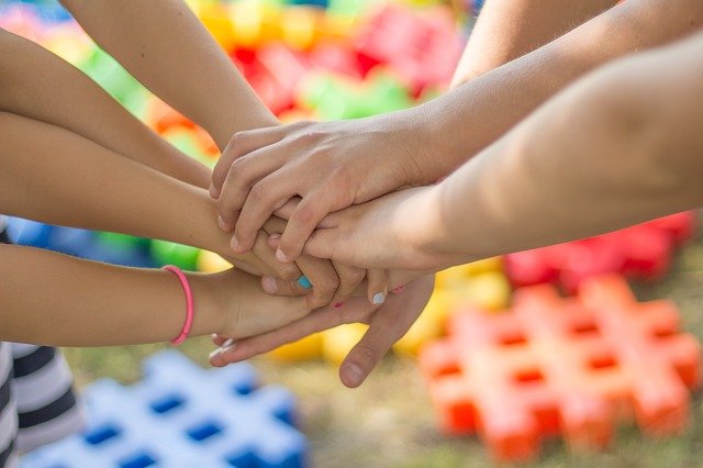 group of young children stacking their hands on top of one another.