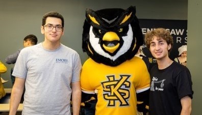 Two male students standing on either side of KSU mascot, Scrappy the Owl