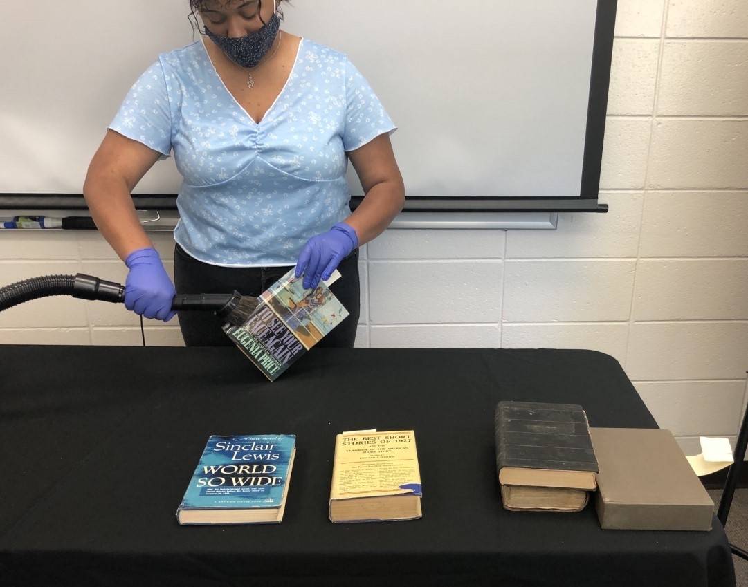 Léla Calixte uses a vacuum to clean mold from rare books.