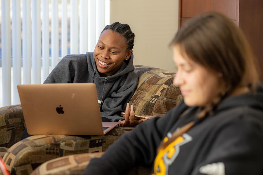 ksu freshman students sitting on the couch studying with their laptops.