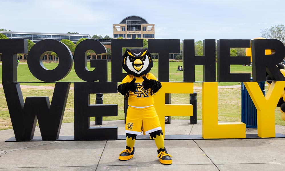 scrappy posing in front of the "together we fly" sign.