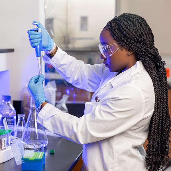 ksu student in lab safety gear working on a lab experiment