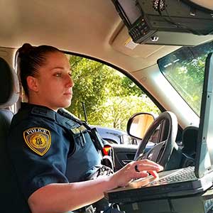 officer in vehicle typing on computer.