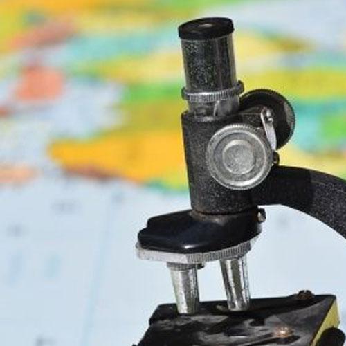 A microscope with a blurred background of a colorful world map.