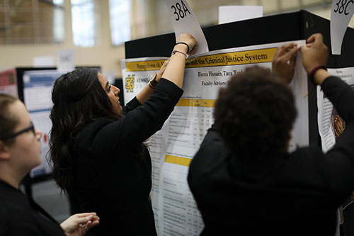 Student hanging a poster for an Academic Conference