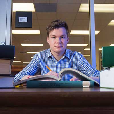 student between books at table