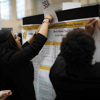 students hanging signage for exhibit booth