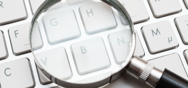 keyboard with a magnify glass sitting on top of it.