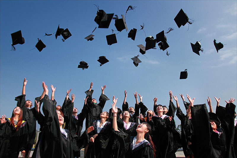 a large group of graduates tossing there graduation caps into the air