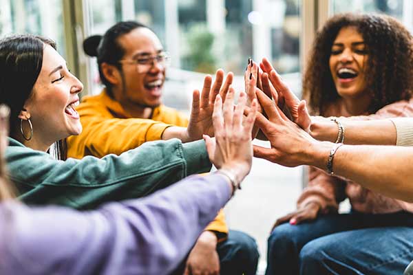 Students stacking hands-Group of diverse friends having fun unity together 