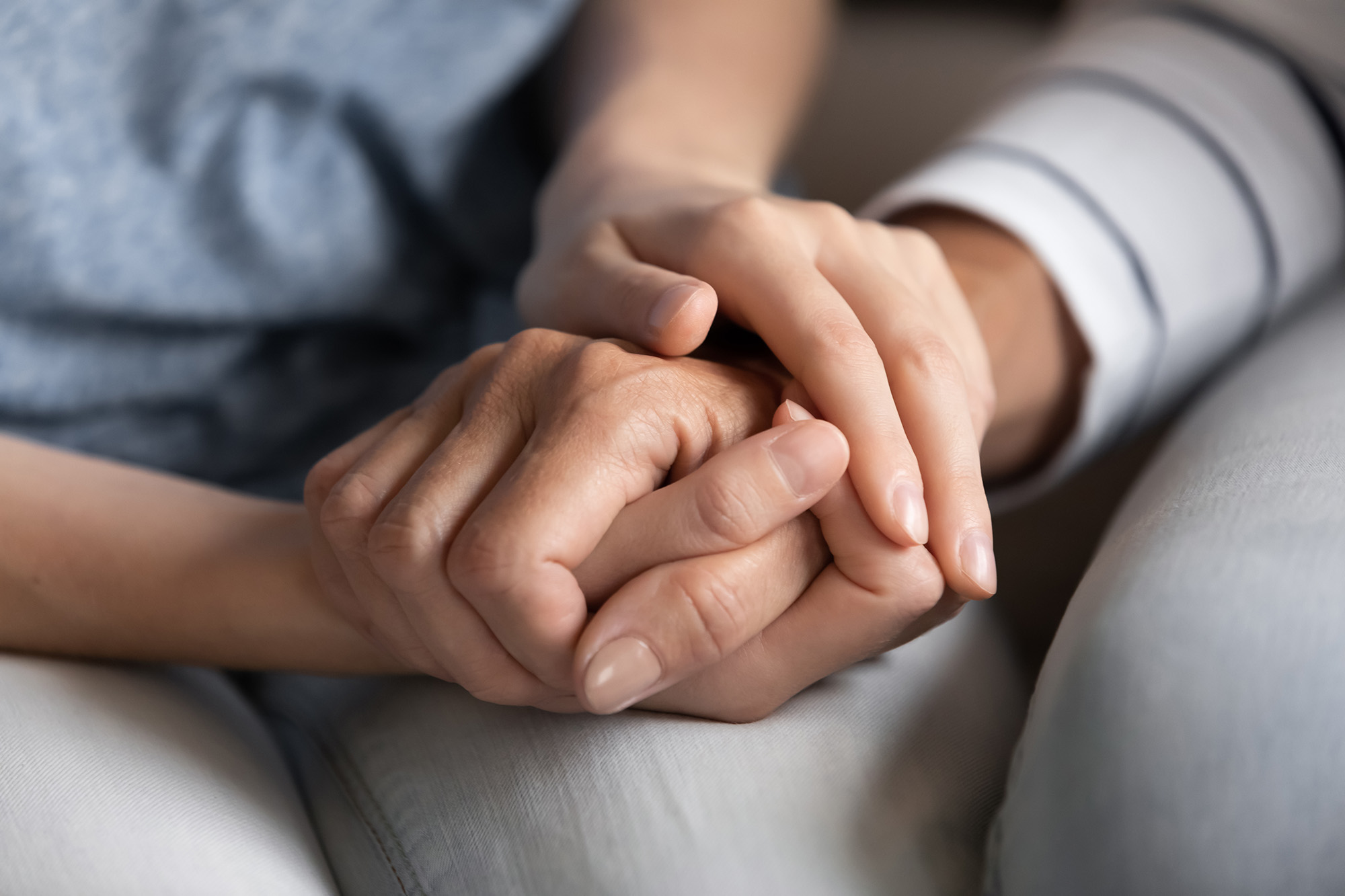 Close up of woman holding tight hand of another woman