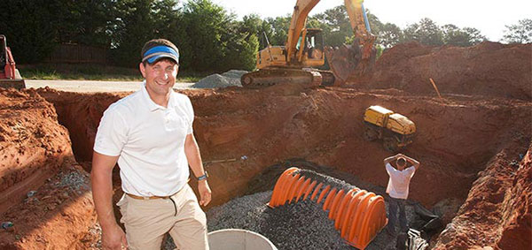 A civil engineer is positioned in a hole, utilizing construction equipment, demonstrating work on a building site.