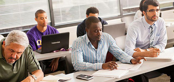 A diverse group of students attentively sitting at desks in a classroom, focused on their studies and discussions