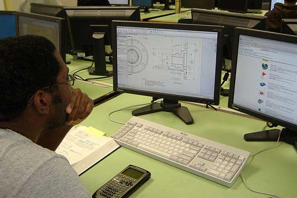 student at desk in front of computer screens