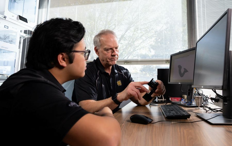 A student and professor discussing a project and working on a computer at KSU.