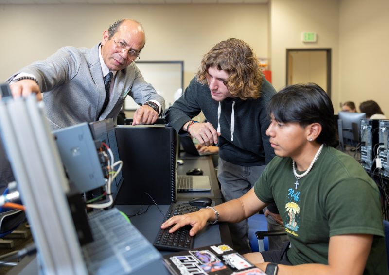 KSU professor guides students through hands-on learning with computer systems in an electrical engineering lab.