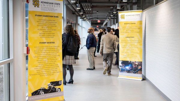 A hallway at Kennesaw State University with yellow engineering banners and people walking in the background.