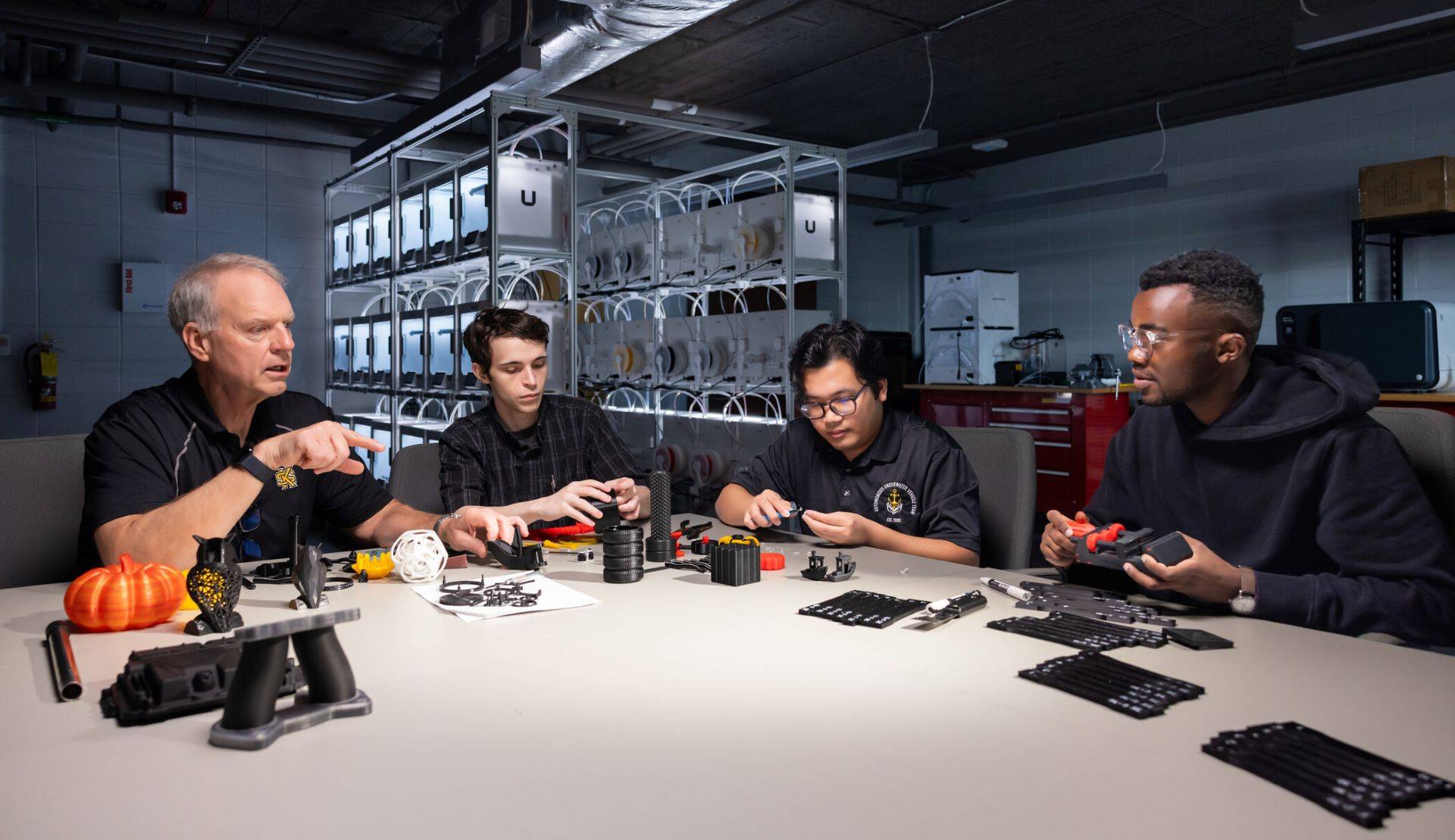 Students and a professor at KSU's SPCEET collaborate on a project involving 3D-printed components in a technology lab.