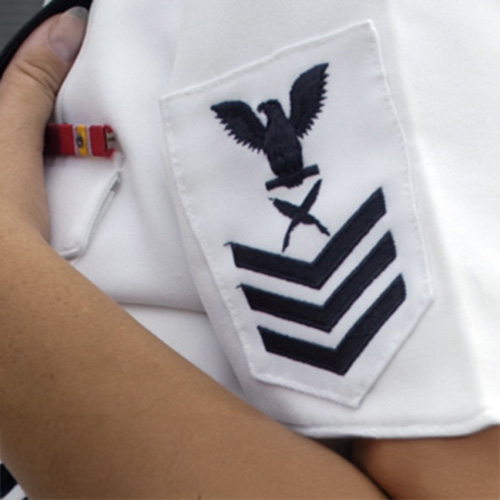 A Kennesaw State ROTC cadet in uniform grips a pen and badge, illustrating the values of discipline and honor in service.