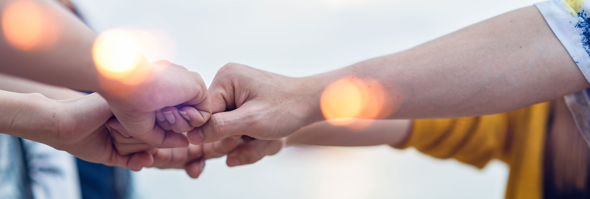 A close-up of several people bumping fists together in a show of teamwork and camaraderie.